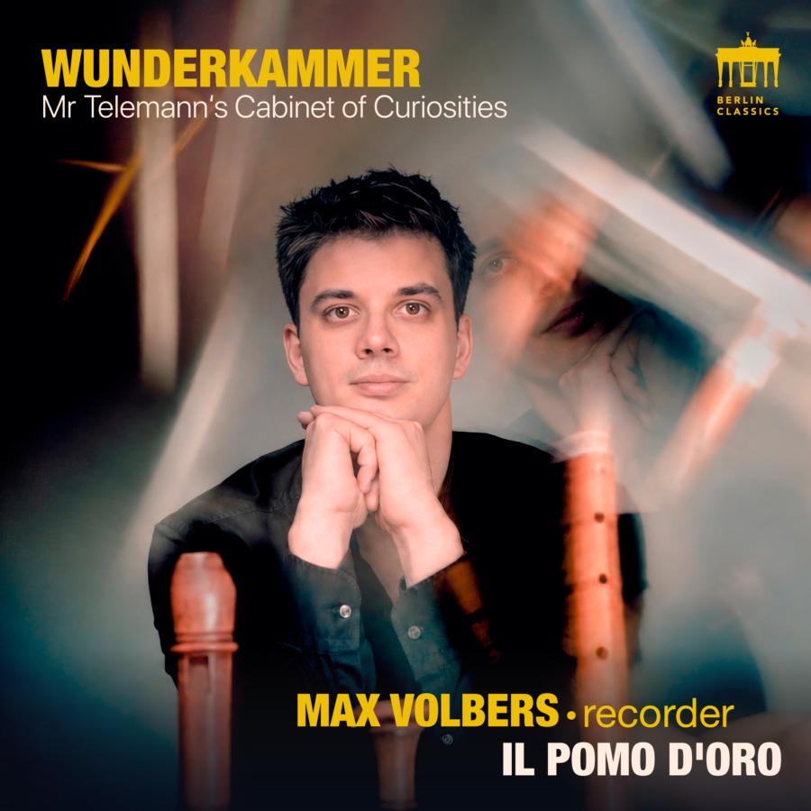 Release-Cover „WUNDERKAMMER – Mr. Telemann’s Cabinet of Curiosities“ von Blockflötist Max Volbers mit Il Pomo d’Oro. Künstlerisches Porträt in Nahaufnahme mit nachdenklichem Blick, die Hände unter dem Kinn verschränkt. Mehrere Blockflöten stehen unscharf im Vordergrund, Spiegelungen und Lichtreflexe erzeugen eine geheimnisvolle Atmosphäre in warmen Braun- und dunklen Blautönen. Typografie mit Werktitel und Künstlernamen ist im Cover integriert.