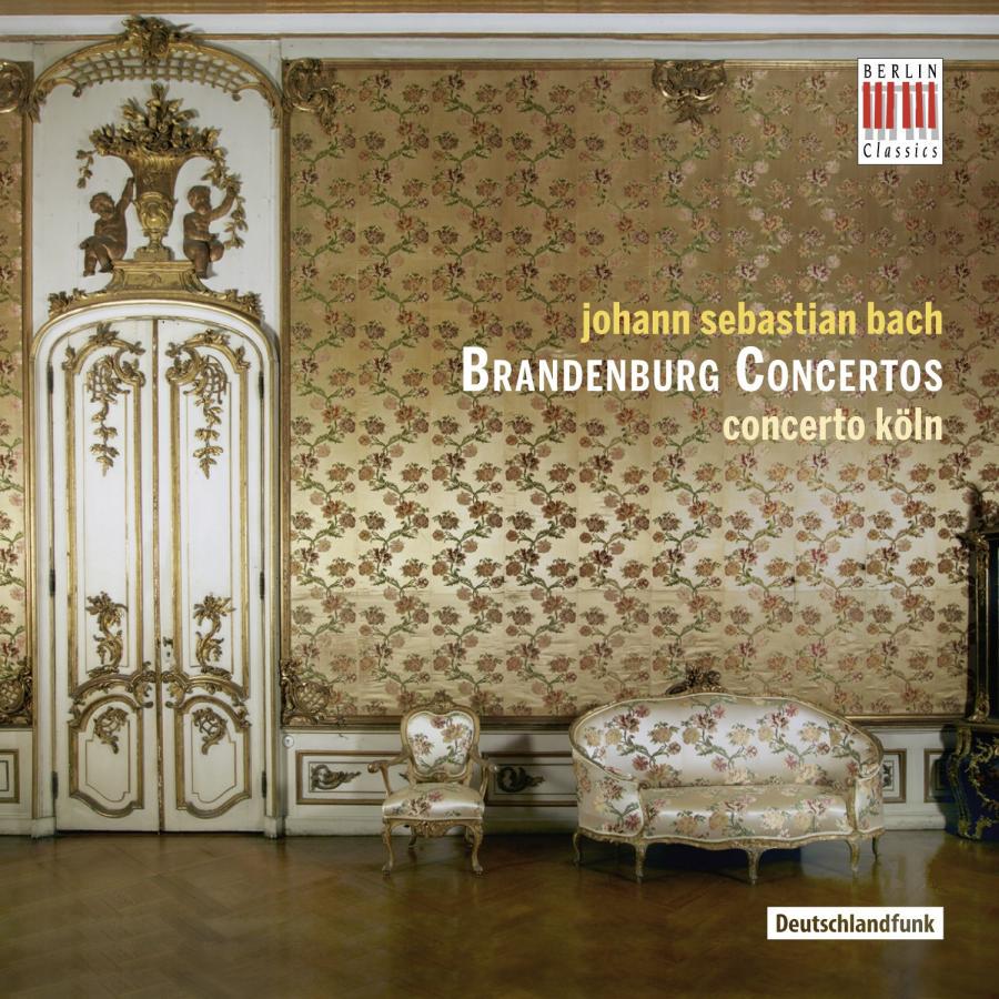 Release-Cover „Bach: Brandenburg Concertos“ von Johann Sebastian Bach mit Concerto Köln. Historischer Salon mit floral gemusterter Wand, verzierter Tür, Sessel und Sofa; warme Beige-, Gold- und Rosatöne, frontale Raumansicht und elegante barocke Atmosphäre.