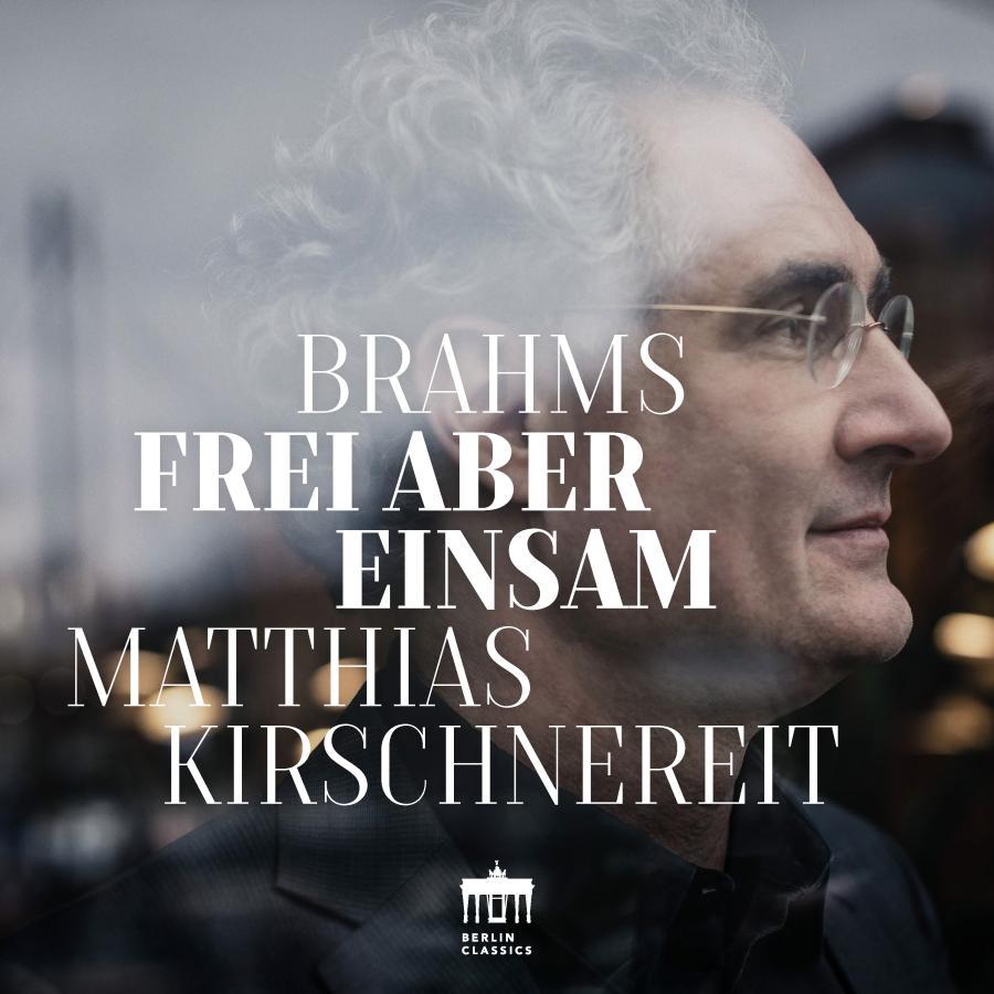 Release-Cover „Brahms: Frei aber Einsam“ von Pianist Matthias Kirschnereit. Nahes Seitenprofil von Matthias Kirschnereit mit Brille, überlagert von großer weißer Typografie; kühle Grau- und Blautöne, weiche Unschärfe und nachdenkliche, intime Stimmung.