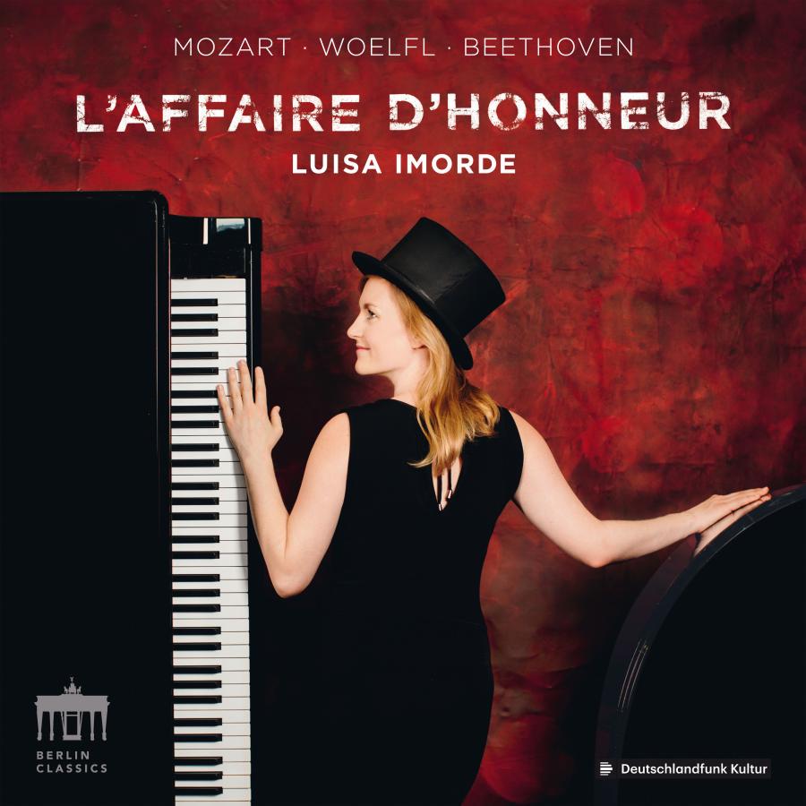 Release-Cover „L’affaire d’honneur“ von Pianistin Luisa Imorde mit Werken von Mozart, Woelfl und Beethoven. Porträt von hinten mit seitlichem Blick mit schwarzem Zylinder zwischen Flügel und Klaviertastatur vor rotem Hintergrund; seitliche Pose, dramatische Farben und theatralische Wirkung.