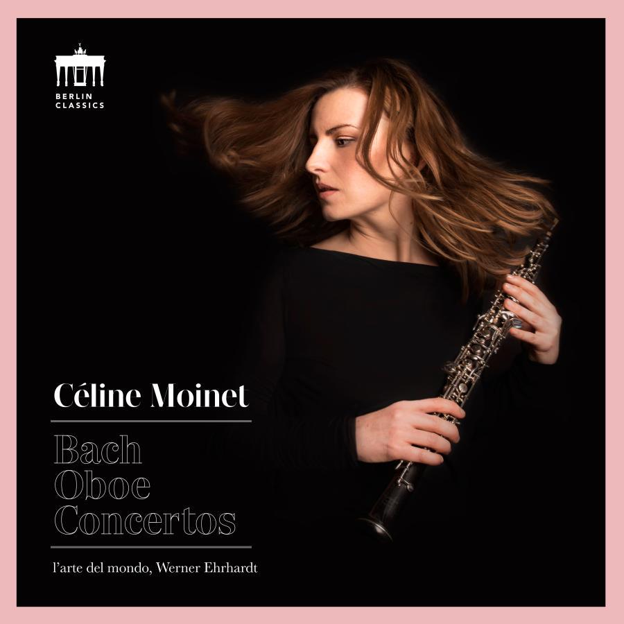 Release-Cover „Bach: Oboe Concertos“ von Oboistin Céline Moinet. Dunkles Porträt mit Oboe in den Händen und bewegtem Haar vor schwarzem Hintergrund, eingefasst von rosafarbenem Rahmen; kontrastreiches Licht und elegante Musikerinnen-Pose.