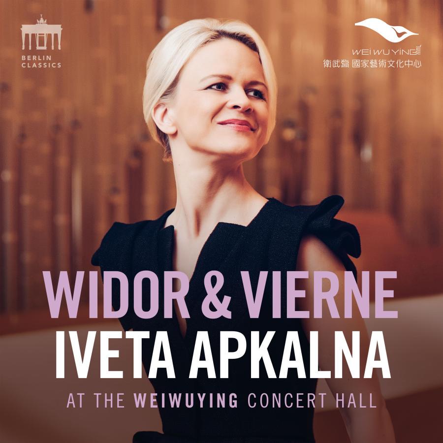 Release-Cover „Widor & Vierne“ von Organistin Iveta Apkalna, aufgenommen in der Weiwuying Concert Hall. Warmes Porträt vor holzfarbenem Hintergrund, der Blick geht lächelnd zur Seite; weiches Licht, Braun- und Rosatöne und elegante Konzertsaalwirkung.