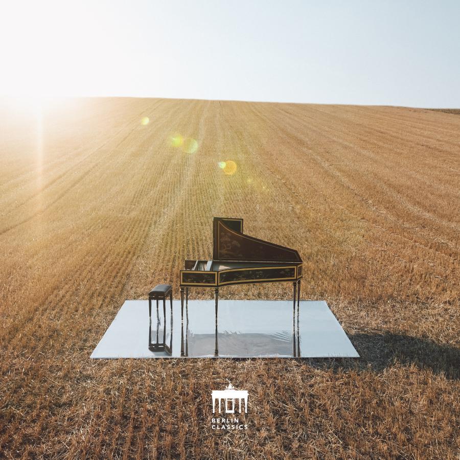 Release-Cover „Bach: The Brandenburg Concertos“ von Organist und Cembalist Jörg Halubek und dem il gusto barocco. Ein Cembalos steht auf einer reflektierenden Fläche in einem goldenen Feld bei tief stehender Sonne; warme Naturfarben, Vogelperspektive aus der Ferne und ruhige, offene Landschaftswirkung.