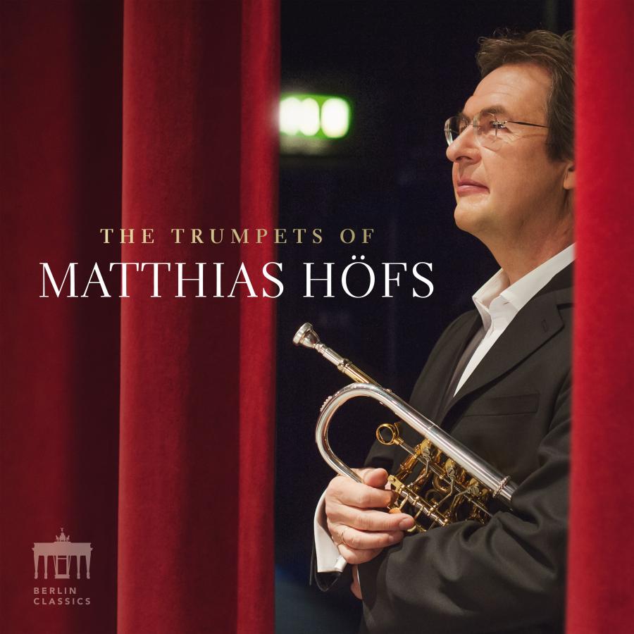 Release-Cover „The Trumpets of Matthias Höfs“ von Trompeter Matthias Höfs. Höfs im Anzug steht mit Trompete zwischen einem halb geöffneten rotem Bühnenvorhang; warme Rot- und Goldtöne, seitliches Porträt und feierliche Konzertatmosphäre.