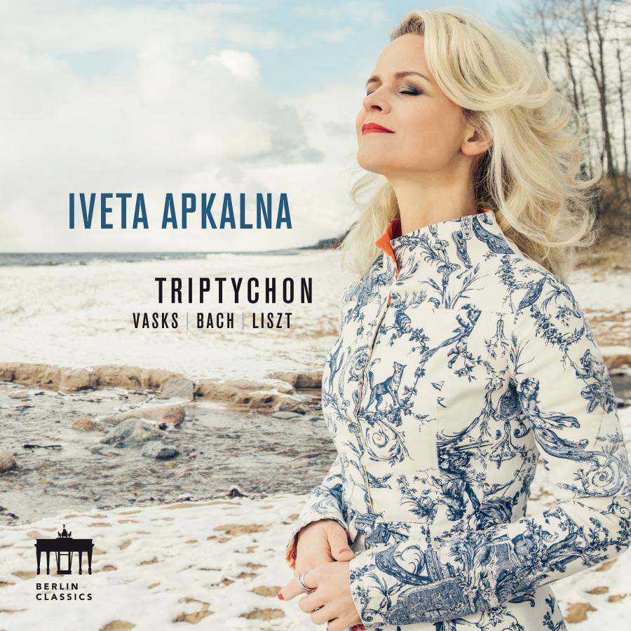 Release-Cover „Triptychon“ von Organistin Iveta Apkalna mit Werken von Vasks, Bach und Liszt. Iveta Apkalna am winterlichen Strand, sie trägt eine helle gemusterte Jacke und blickt mit geschlossenen Augen zur Seite; kühle Naturfarben, weiches Licht und ruhige Küstenstimmung.