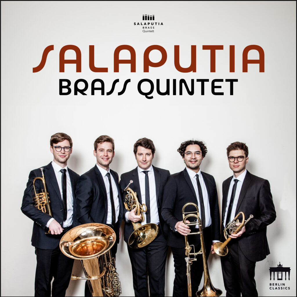 Porträt von dem Bläserensemble Salaputia Brass. Sie tragen feierliche Anzüge, mit ihren Instrumenten in der Hand. Die stehen in kontrastreichem Licht vor heller Wand.
